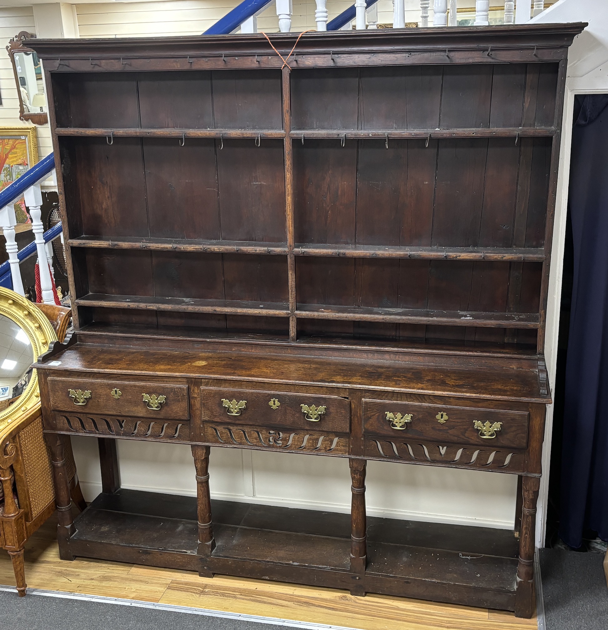 An 18th century oak potboard dresser with boarded rack and pierced apron, width 186cm, depth 43cm, height 198cm